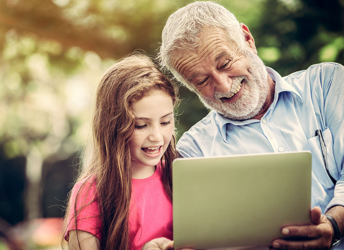 Read Our Reviews - Closeup Portrait of a Cheerful Grandfather Using a Tablet with his Young Granddaughter at a Park on a Sunny Day